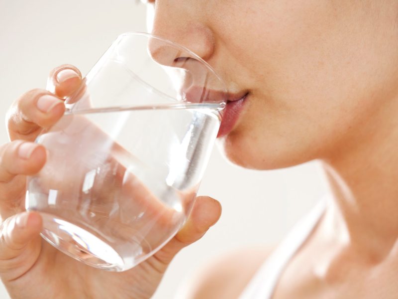 Nahaufnahme auf eine Person, die aus einem Glas Wasser trinkt.