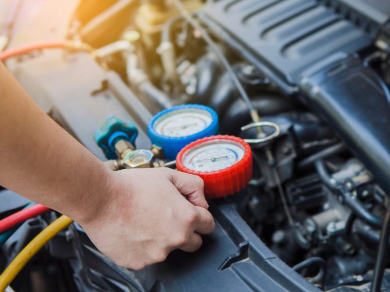 Mann nimmt Wartung an der Klimaanlage beim Auto vor.