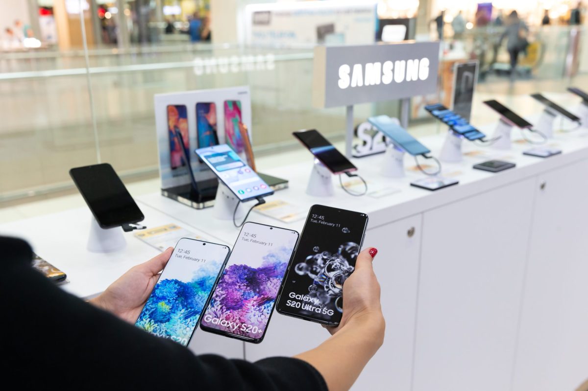 Person hält mehrere Samsung-Handys vor einer Auslage.