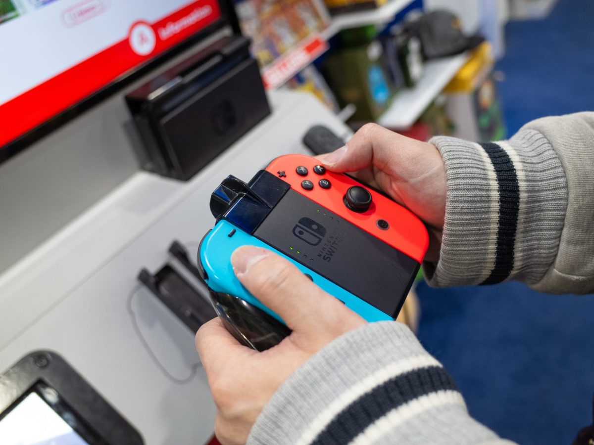 Eine Person hält in einem Laden einen NIntendo Switch-Controller in der Hand.