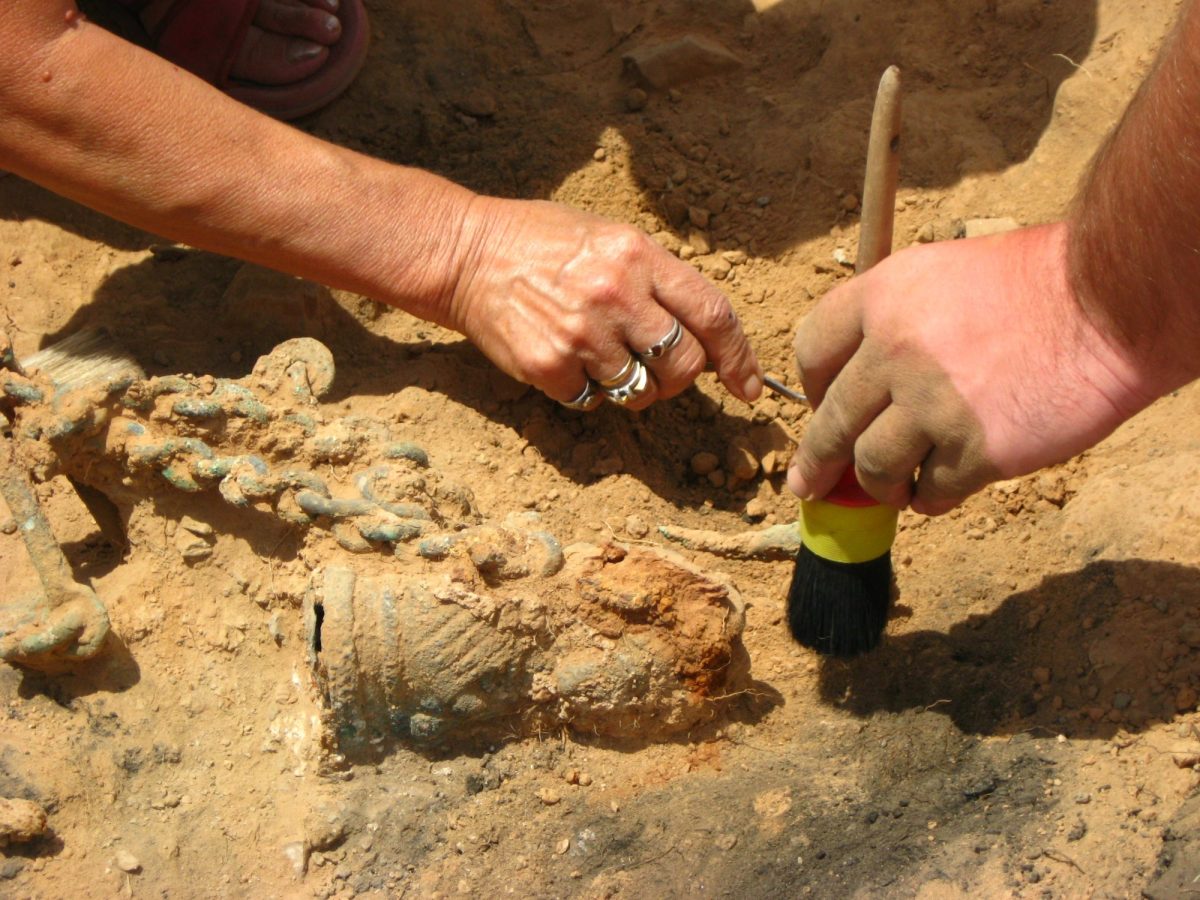 Menschen arbeiten mit Werkzeug an einem archäologischen Fund.