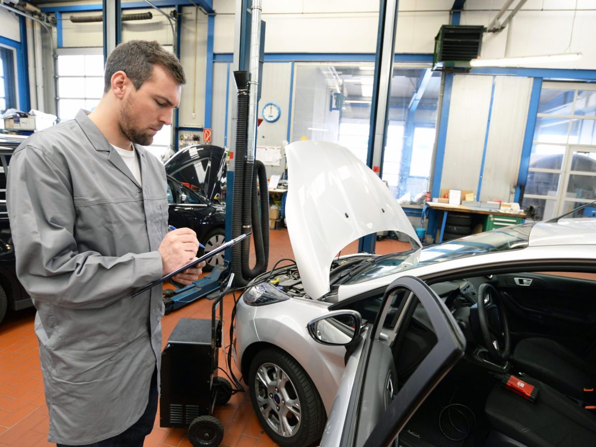 TÜV-Prüfer steht an einem Auto.