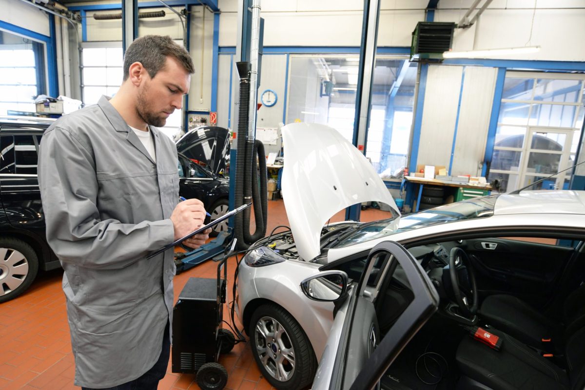 Prüfer vom TÜV mit einem Auto und Klemmbrett.