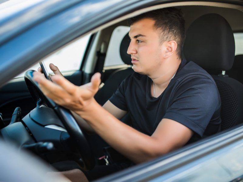 Autofahrer sitzt im Auto und macht eine ungläubige Geste.