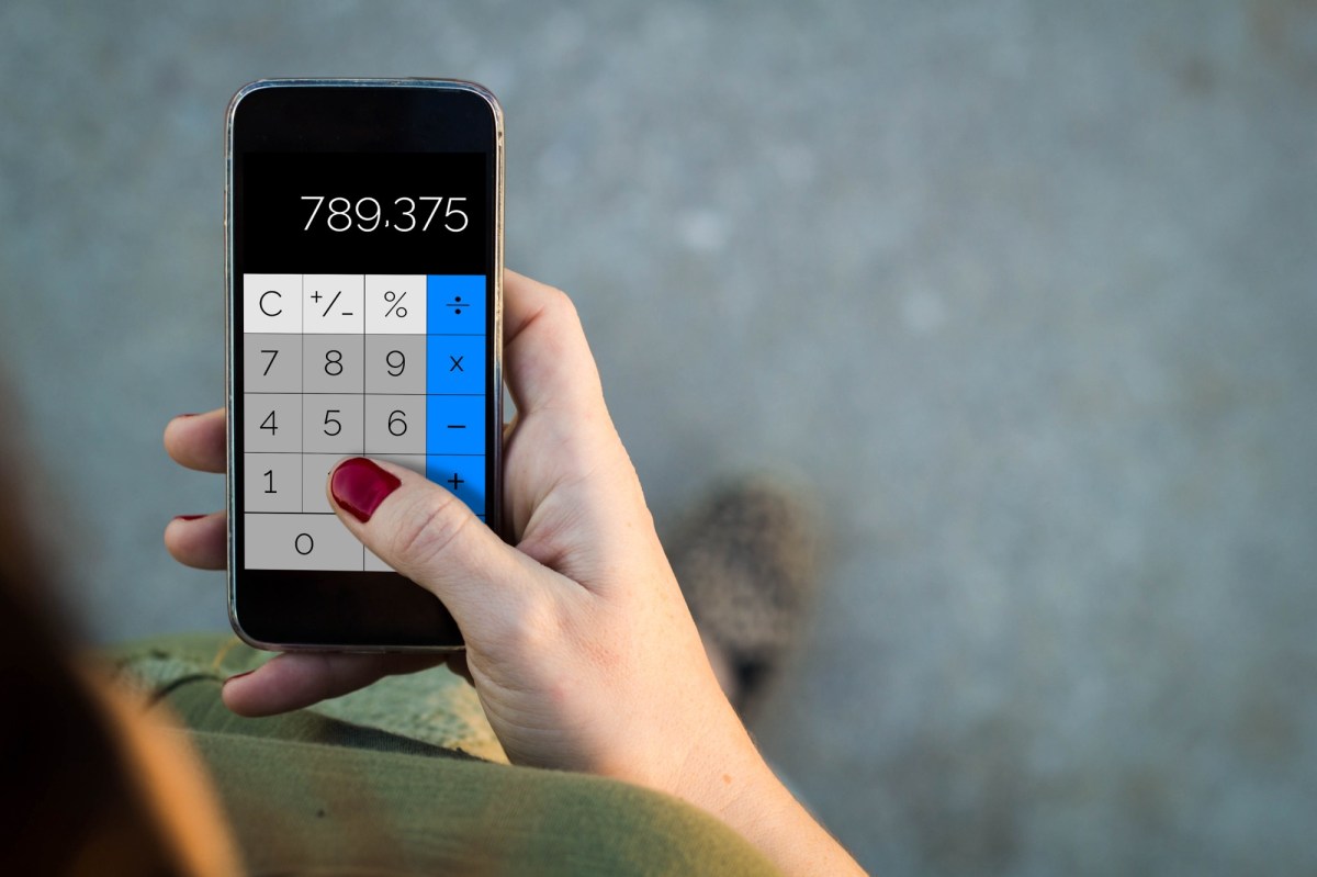 Frau nutzt eine Taschenrechner-App auf dem Handy.