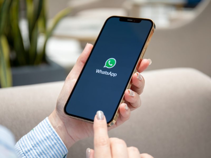 Person hält ein Smartphone, auf dem das WhatsApp-Symbol angezeigt wird.