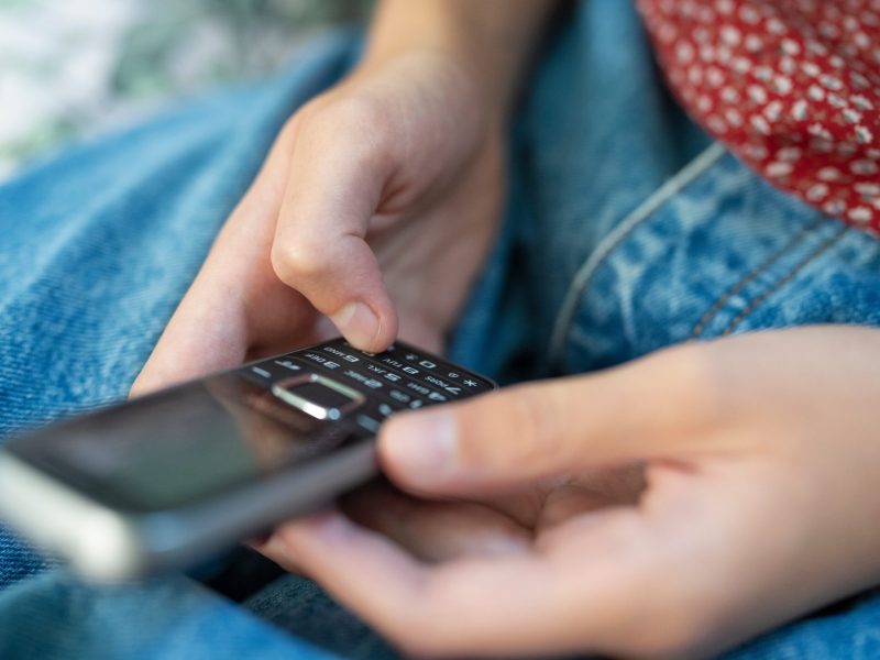 Person mit einem "Dumbphone" in der Hand.