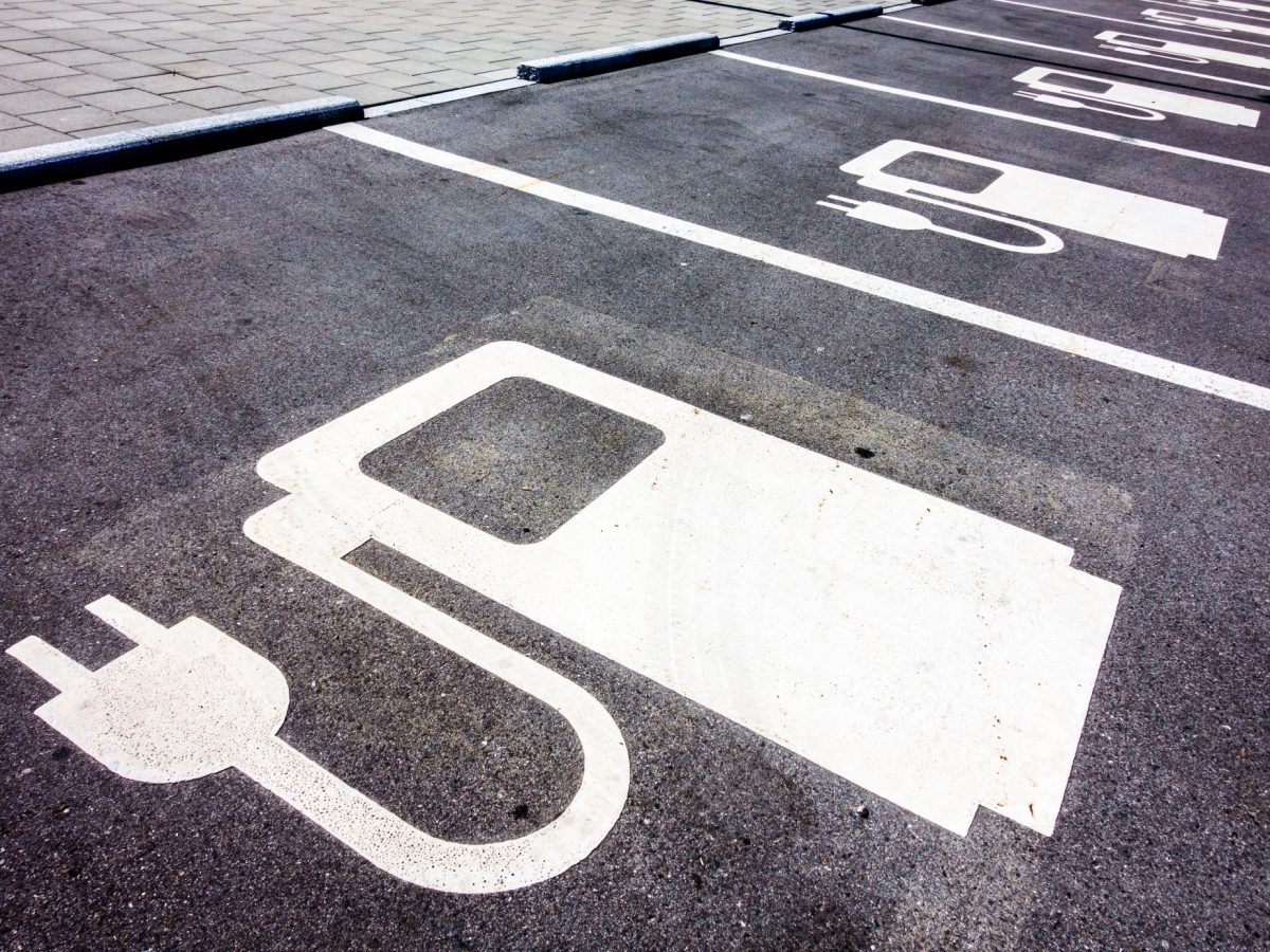 Symbol einer Ladesäule für Elektroautos ist auf den Straßenbelag gezeichnet.