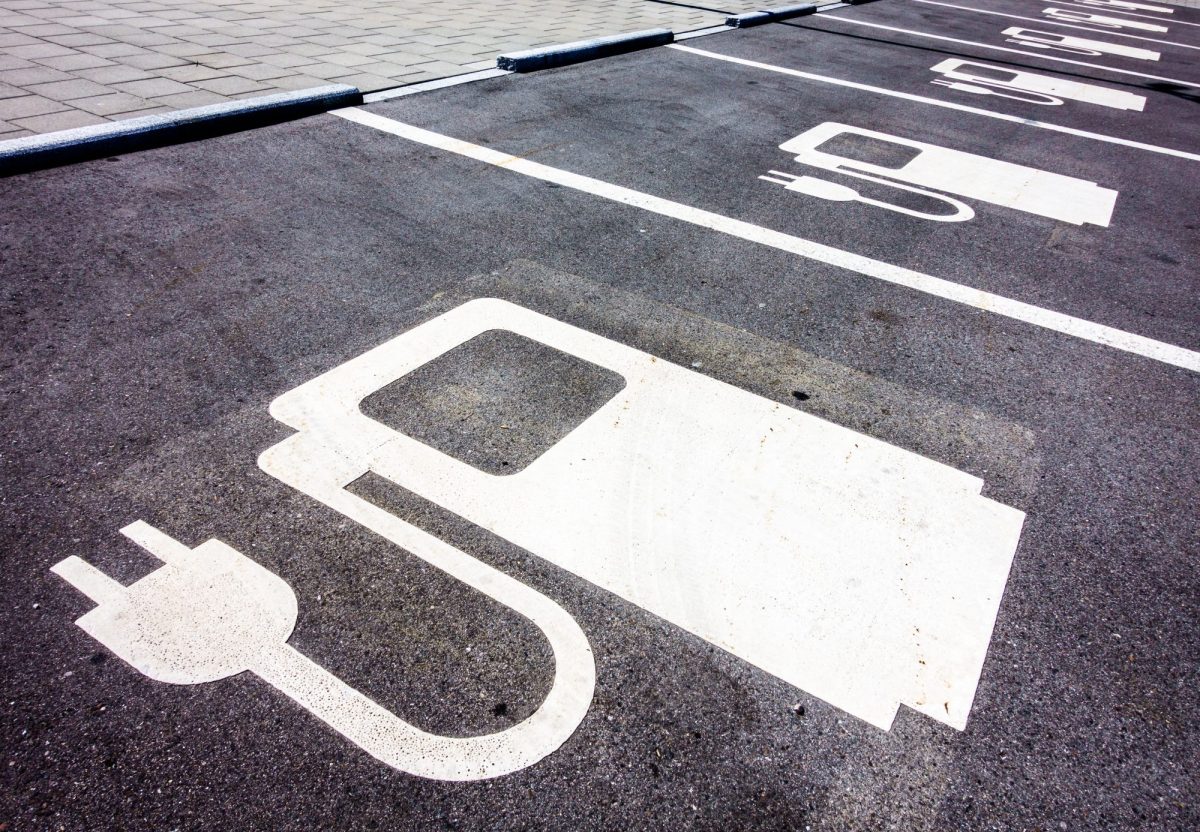 Symbol einer Ladesäule für Elektroautos ist auf den Straßenbelag gezeichnet.