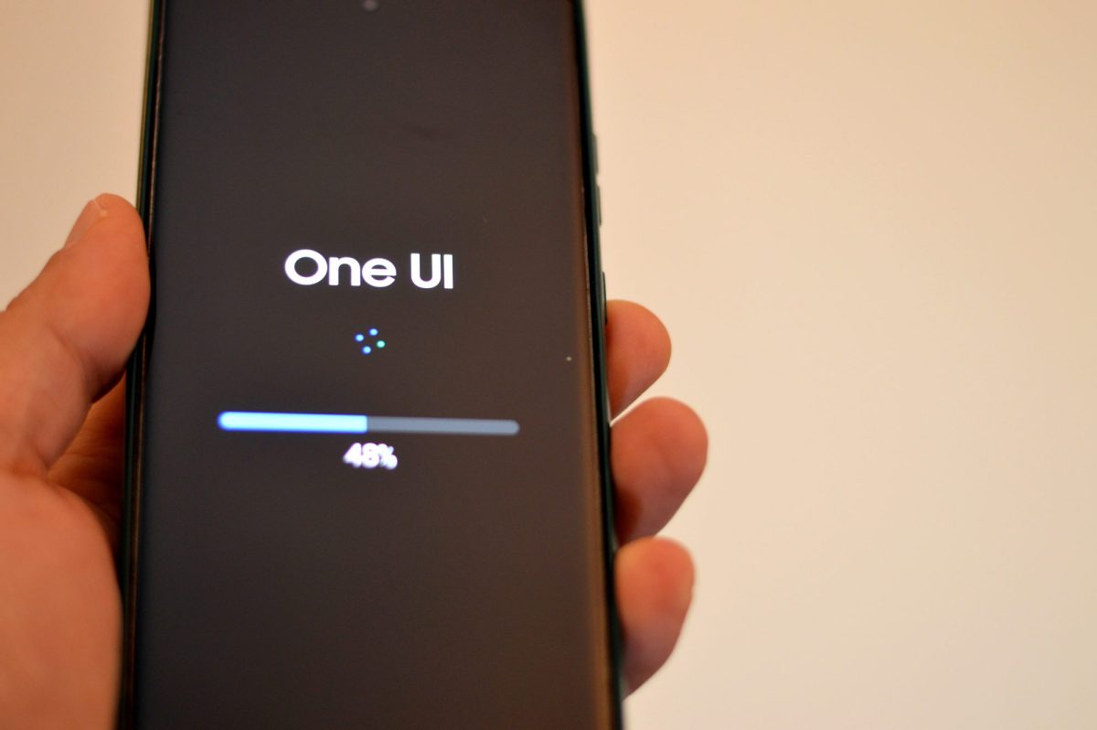 Person hält ein Samsung Galaxy-Handy in der Hand, auf dem eine neue One UI-Version geladen wird. (Symbolbild)