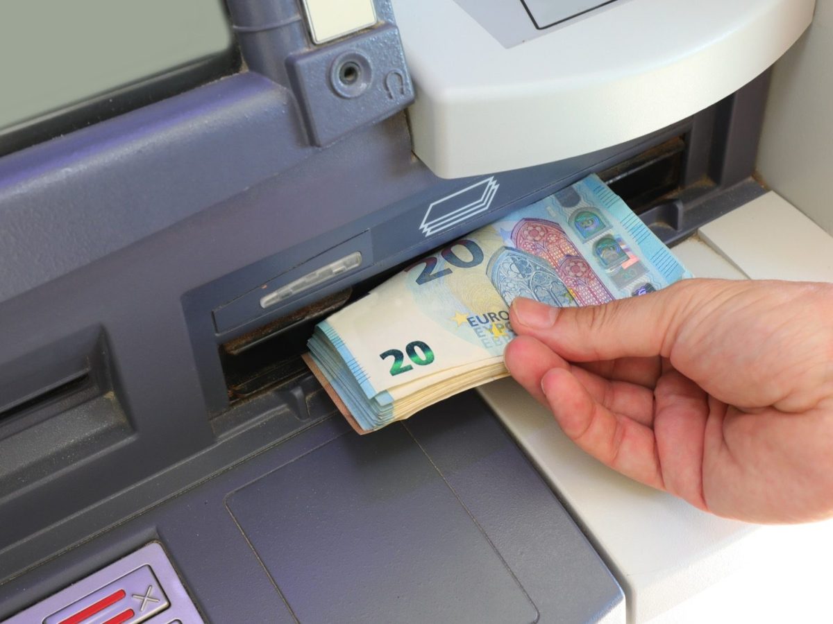 Person hebt Geld am Geldautomaten ab
