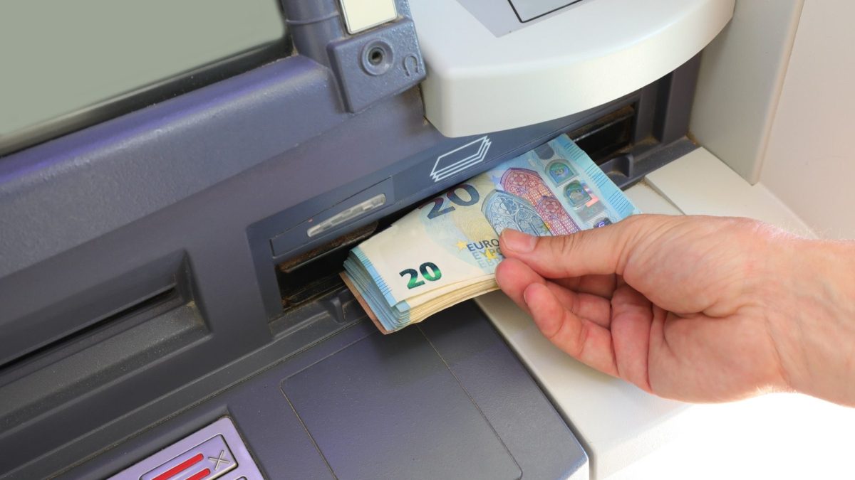 Person hebt Geld am Geldautomaten ab
