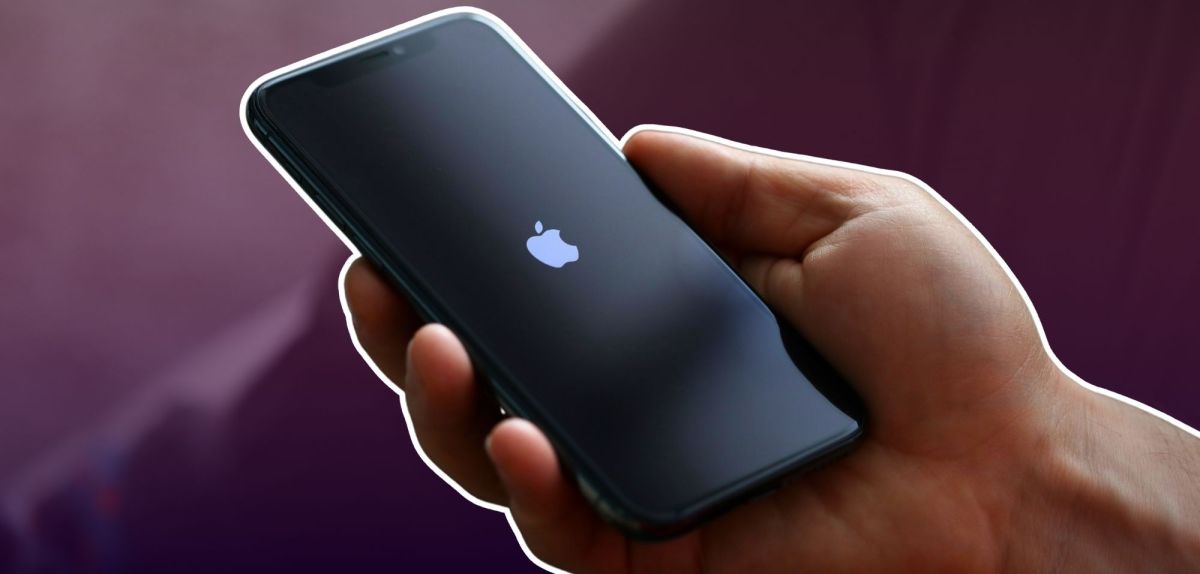 Hand hält ein iPhone mit Apple-Logo auf dem Display.
