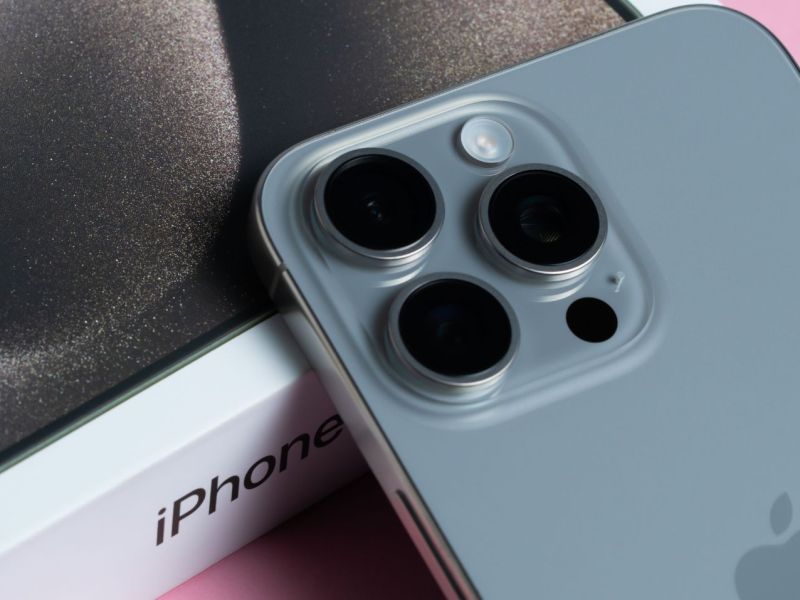 iPhone samt Karton auf pinkem Untergrund.